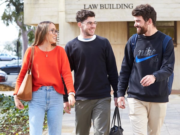 Group of three students walking away from the LIT Law Building