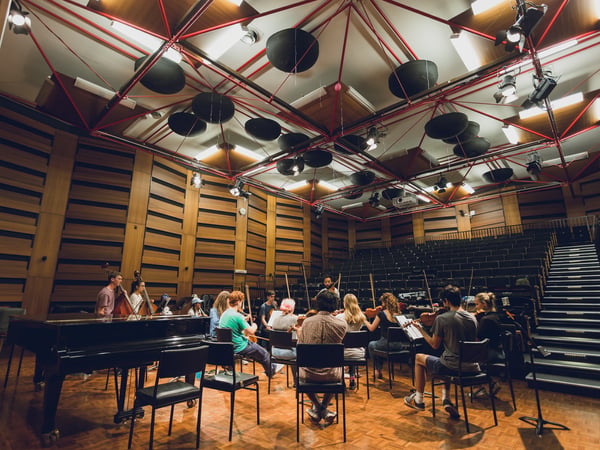 A group of students playing various string instruments in a studio