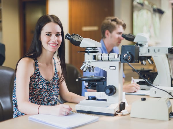 Seated students utilising microscopes