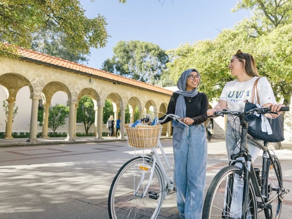 Two students standing next to bicycles on campus